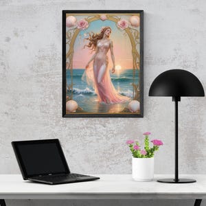 Op de afbeelding: Een ingelijste kunstdruk toont een vrouw in een roze jurk in de zee bij zonsondergang. Het kunstwerk heeft een gouden boog met rozen en schelpen. De print staat op een muur boven een wit bureau met een laptop, een lamp en een kleine potplant.