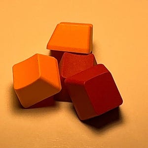 May include: A collection of colorful, square-shaped blocks in shades of orange and red. The blocks are stacked together, creating a visually appealing arrangement. The image is well-lit, highlighting the vibrant colors and geometric shapes.
