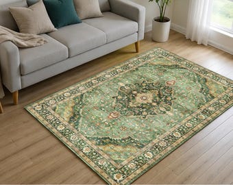 May include: A rectangular area rug featuring a distressed sage green base with a central medallion and intricate floral border patterns in shades of dark green, cream, and muted rust, laid flat on a light brown wooden floor surface.