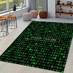 Puede incluir: Una alfombra rectangular con fondo negro y patrón de código alfanumérico verde. La alfombra presenta el texto "SYSTEM FAILURE" en un cuadro blanco, creando un diseño inspirado en la tecnología.