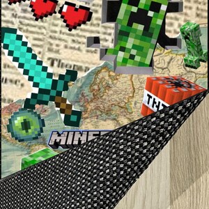 May include: A digital art piece featuring Minecraft characters and elements. The image includes a pixelated green Creeper, a diamond sword, red hearts, and a TNT block. The word "BOOM" is displayed in a comic book style, with the word "MINE" visible.