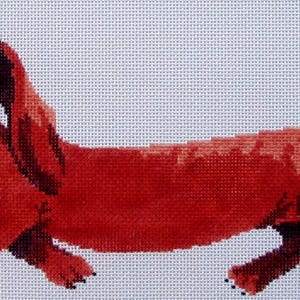 May include: A needlepoint canvas featuring a stylized, long-bodied dachshund dog with reddish-brown fur, large expressive eyes, and long floppy ears. The design is rendered in a pixelated grid pattern on a white background, showing the dog in profile.