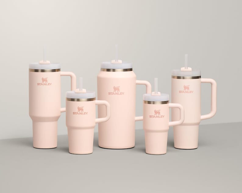May include: A collection of five pink insulated tumblers and mugs with white lids and straws. Each tumbler features a handle and the "STANLEY" logo. The sizes vary, offering options for different beverage needs.