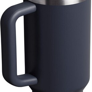 Puede incluir: Un vaso t&eacute;rmico azul marino con asa y tapa transparente. La tapa tiene un cierre abatible marr&oacute;n. El vaso tiene un borde plateado y un logotipo en la parte inferior. Este termo de viaje est&aacute; dise&ntilde;ado para mantener las bebidas calientes o fr&iacute;as.