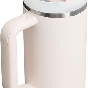 May include: A light pink insulated tumbler with a handle and a white lid. The lid has a pink slider and a clear straw. The tumbler is designed to keep beverages cold or hot.