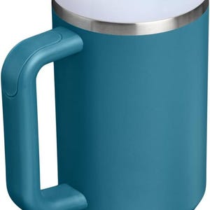 K&ouml;nnte beinhalten: T&uuml;rkis isolierter Becher mit Henkel, wei&szlig;em Deckel und wiederverwendbarem Strohhalm. Der Becher hat einen Edelstahlrand und einen Griff zum einfachen Tragen. Perfekt f&uuml;r hei&szlig;e oder kalte Getr&auml;nke.