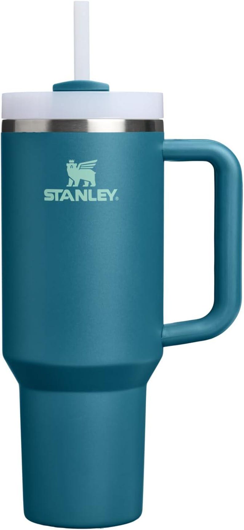 K&ouml;nnte beinhalten: T&uuml;rkisfarbener Stanley-Becher mit wei&szlig;em Deckel, Griff und Strohhalm. Der Becher hat das Stanley-Logo in Gr&uuml;n. Dieser isolierte Reisebecher ist so konzipiert, dass er Getr&auml;nke stundenlang kalt oder hei&szlig; h&auml;lt. Fassungsverm&ouml;gen ca. 1,2 Liter.