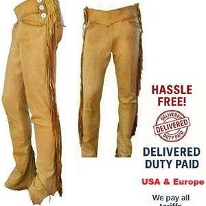 Puede incluir: Chaps de cuero color canela con flecos en los laterales. Los chaps tienen cintura alta y cierre de botón. La imagen muestra dos vistas de los chaps, una lateral y otra frontal. Prendas de vestir de estilo western.