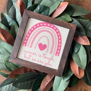 May include: A framed canvas with a pink rainbow design and the text "cancer is tough, but so are you".
