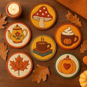 May include: A collection of round, embroidered coasters with autumn-themed designs. The coasters feature images of a mushroom, teapot, maple leaf, coffee cup, pumpkin spice latte, and a pumpkin with a heart. The color palette includes orange, yellow, and brown.