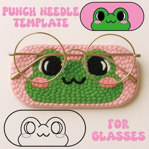 May include: A pink, crocheted glasses case with a green frog face design and gold-rimmed glasses. The case has the text "PUNCH NEEDLE TEMPLATE" and "FOR GLASSES" in pink. The frog has black eyes and pink cheeks.
