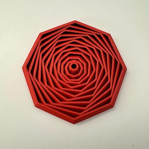 May include: A red, geometric, multi-layered object with an octagonal shape. The design features concentric layers, creating a spiral effect towards the center. The object is a vibrant red color.