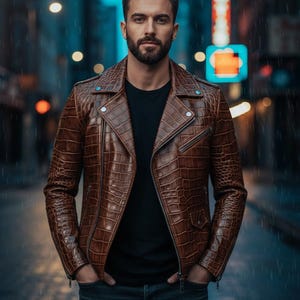 Puede incluir: Chaqueta de cuero marr&oacute;n con efecto piel de cocodrilo, cierre de cremallera y detalles plateados. Se lleva sobre una camiseta negra y vaqueros azul oscuro. El fondo es una calle de la ciudad de noche, con farolas y lluvia.