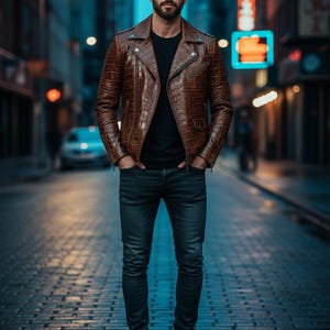 Puede incluir: Chaqueta de cuero marr&oacute;n con un patr&oacute;n texturizado, combinada con una camiseta negra y vaqueros oscuros. La chaqueta presenta un estilo motero cl&aacute;sico con cuello de solapa y detalles de cremallera. La persona lleva botas negras.