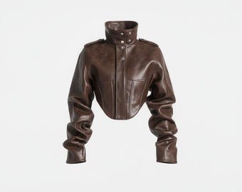 Peut inclure: Veste en cuir marron avec un col montant et des boutons. La veste a des manches longues et une taille courte. Le cuir a un aspect légèrement vieilli. La veste est présentée sur un fond blanc.
