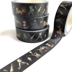 Könnte beinhalten: Vier Rollen schwarzes Washi-Klebeband mit bunten Illustrationen von fantastischen Kreaturen. Das Band ist abgewickelt, um das Design zu zeigen.