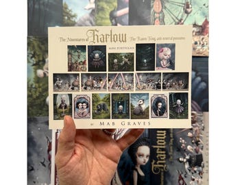 May include: A mini portfolio titled The Adventures of Harlow: The Raven King, and several possums by Mab Graves. The cover features a grid of small, dark, illustrative art prints depicting whimsical characters, animals, and scenes in a muted palette.