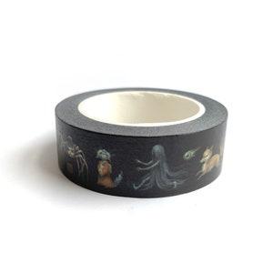 May include: A roll of black washi tape with a repeating pattern of a spider, a small figure in a brown dress, a long-haired figure, a green orb, and a fox.