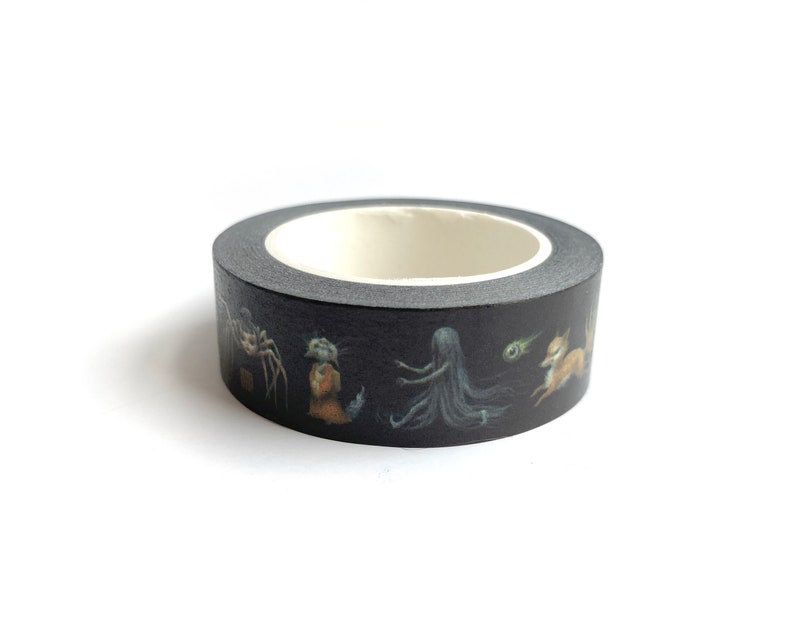 May include: A roll of black washi tape with a repeating pattern of a spider, a small figure in a brown dress, a long-haired figure, a green orb, and a fox.