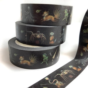 May include: Three rolls of black washi tape with a dark fantasy design. The tape features illustrations of a spider, a fox, and other creatures.