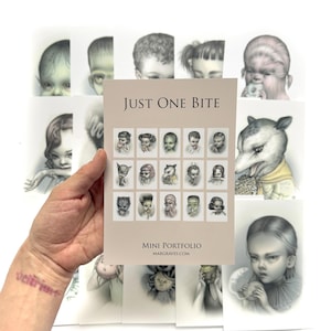 May include: A rectangular paper portfolio titled Just One Bite featuring a grid of fifteen small character illustrations. The cover includes the text Mini Portfolio and Mabgraves.com, with several larger individual character art prints displayed behind it.