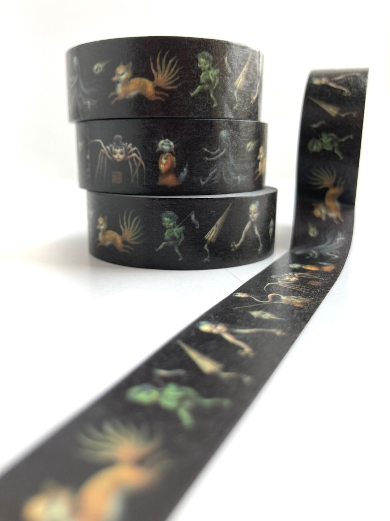 May include: A roll of black washi tape with a repeating pattern of whimsical creatures in shades of green, brown, and white. The tape features a fox, a spider, a goblin, and other fantastical beings.