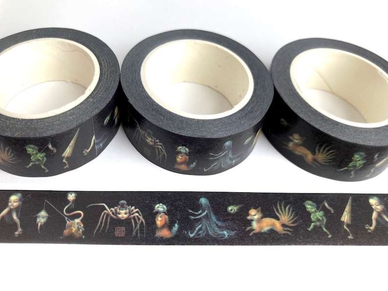 May include: Three rolls of black washi tape featuring a repeating pattern of colourful creatures and figures. The tape is decorated with a variety of mythical creatures, including a spider, a fox, a ghost, and a goblin.