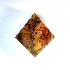 May include: A pyramid-shaped crystal with a brown, orange, and yellow agate pattern.
