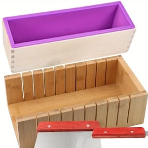 May include: A soap-making kit comprising a purple silicone mould, a wooden mould with vertical dividers, and two stainless steel soap cutters with red handles. Ideal for crafting homemade soaps.