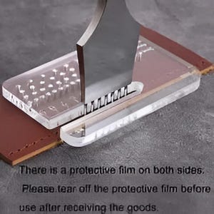 May include: A clear acrylic leather stitching chisel guide with a metal tool inserted into the slot, resting on a brown leather strip. The text on the image reads: There is a protective film on both sides. Please tear off the protective film before use after receiving the goods.
