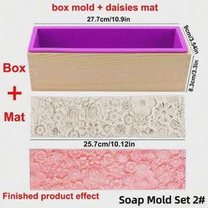 Può includere: Un set di stampi per sapone con una scatola di legno, un inserto in silicone viola e due tappetini floreali. La scatola è lunga 27,7 cm e l'inserto è profondo 9 cm. I tappetini sono lunghi 25,7 cm. Il testo recita "box mold + daisies mat" e "Soap Mold Set 2#".