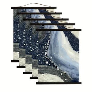 May include: A black framed canvas print with a blue and white abstract design. The design features a white tulle fabric with a blue gradient and white pearl-like embellishments.