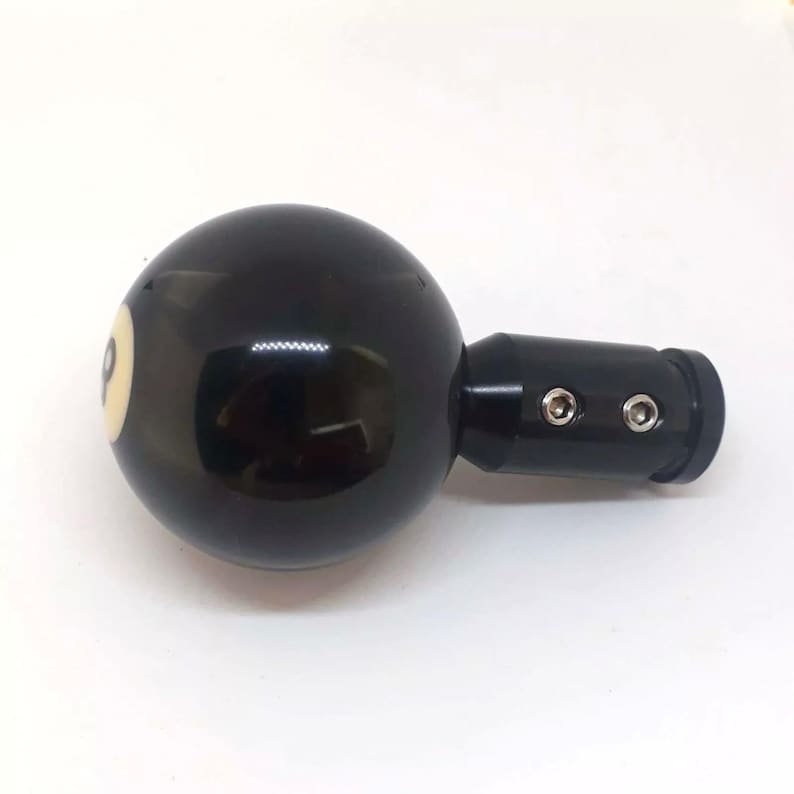 May include: Black and white billiard ball shaped gear shift knob with a black metal base. The ball has a white number eight on it.