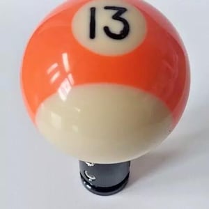 May include: Orange and white billiard ball gear shift knob with the number 13 printed on it.