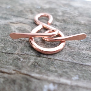 May include: A rose gold infinity symbol charm with a delicate wire design. The charm is made of metal and has a smooth, polished finish.