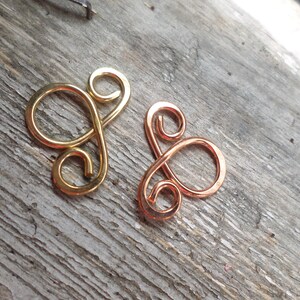 May include: Two wire loops, one gold and one copper, in the shape of a figure eight.