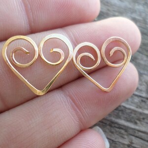 May include: Two gold-colored heart-shaped wire charms with a swirl design.