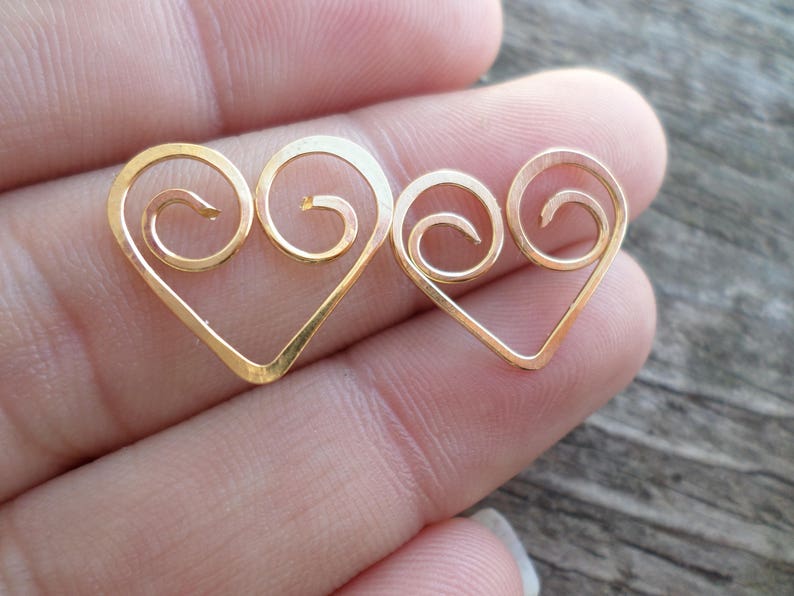 May include: Two gold-colored heart-shaped wire charms with a swirl design.