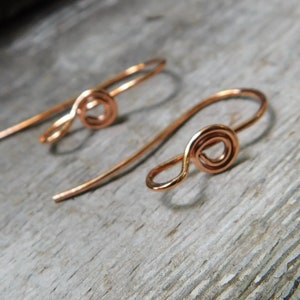 May include: A pair of copper wire earrings with a simple, twisted design. Each earring features a small, circular coil.