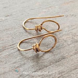 May include: A pair of gold-toned wire earrings with a simple circle design. Each earring has a small, twisted wire detail at the top.