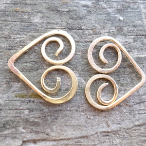 May include: A pair of gold-colored earrings with a heart-shaped design and a double spiral detail.