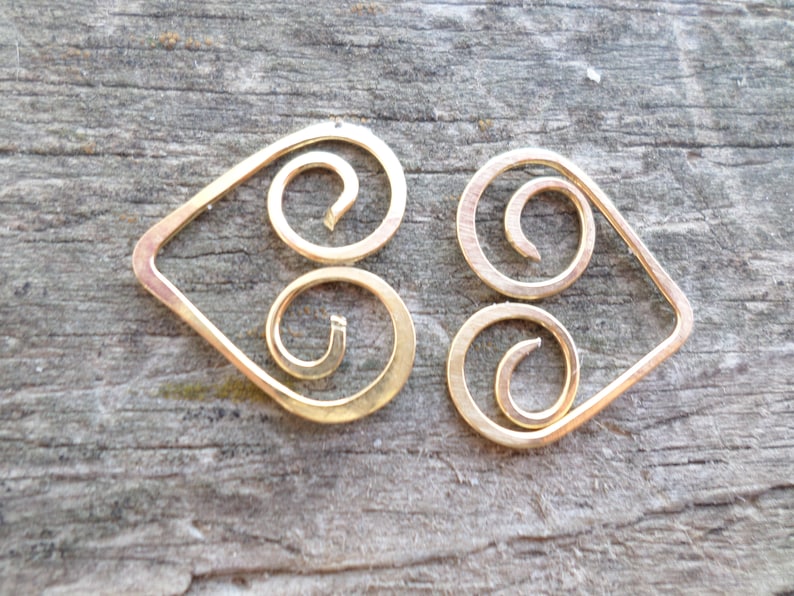 May include: A pair of gold-colored earrings with a heart-shaped design and a double spiral detail.