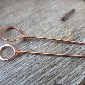 May include: Two copper wire hair pins with a loop at the end of each pin.