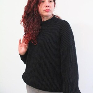 Op de afbeelding: Een zwarte, grove gebreide trui met een ronde hals en lange mouwen. De trui is gemaakt van een zacht, comfortabel materiaal.