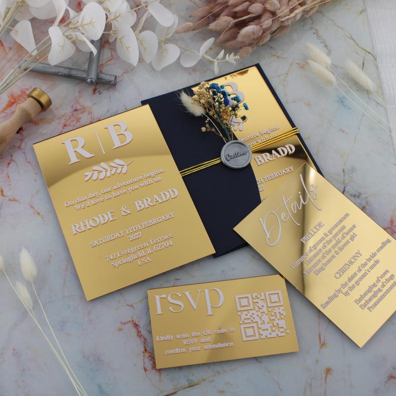 May include: Gold mirror acrylic wedding invitations with white text. The invitations feature the couple's names, wedding date, and location. The RSVP card includes a QR code for guests to confirm their attendance.