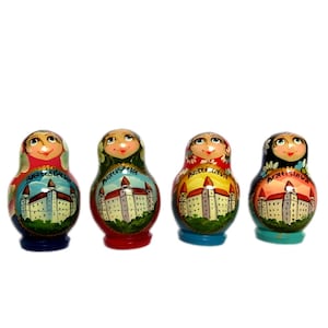 May include: Four colorful nesting dolls with painted faces and castle illustrations. Each doll has a different color base: blue, red, yellow, and teal. The dolls are arranged in a row against a white background.