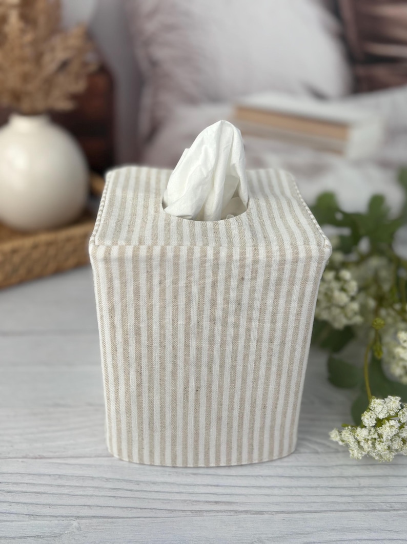 Peut inclure: Une housse de bo&icirc;te &agrave; mouchoirs carr&eacute;e pr&eacute;sentant un motif &agrave; rayures verticales beige clair et blanc. La housse en tissu est con&ccedil;ue pour recouvrir une bo&icirc;te &agrave; mouchoirs standard, avec une ouverture centrale au sommet pour un mouchoir blanc.