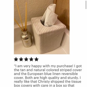 Peut inclure: Une housse de bo&icirc;te &agrave; mouchoirs carr&eacute;e avec un motif &agrave; rayures verticales beige clair et blanc. La housse en tissu recouvre une bo&icirc;te carr&eacute;e, avec un mouchoir blanc d&eacute;passant de l'ouverture sup&eacute;rieure. Un petit diffuseur en verre avec des tiges jaunes.