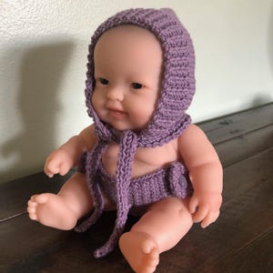 Könnte beinhalten: Ein lila gestricktes Baby-Mützen- und Windelset mit Knopfverschluss. Das Set ist aus weichem Garn gefertigt und perfekt für Neugeborenen-Fotografie-Requisiten.