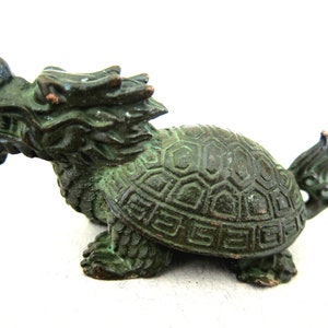 May include: A green bronze statue of a dragon turtle, a mythical creature with a dragon head and a turtle body.